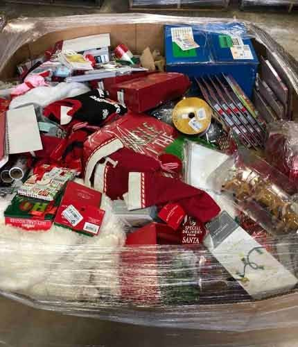 Shrink-wrapped Christmas liquidation pallet containing holiday decor, lights, and festive inventory in a warehouse.